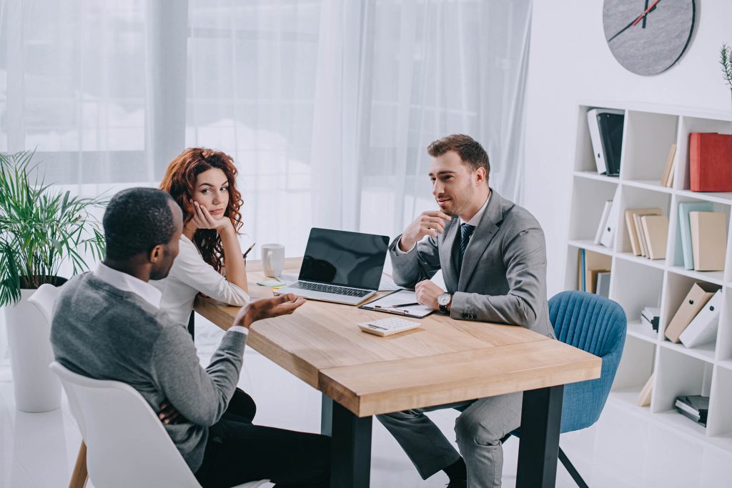 estate agent sitting at table with laptop and talk 38E5QZ8